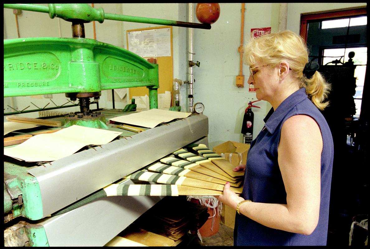 Diane Phillips putting a set of socks into a steam pressing machine at Corgi Hosiery Ltd factory, Ammanford, 1 July 2002.