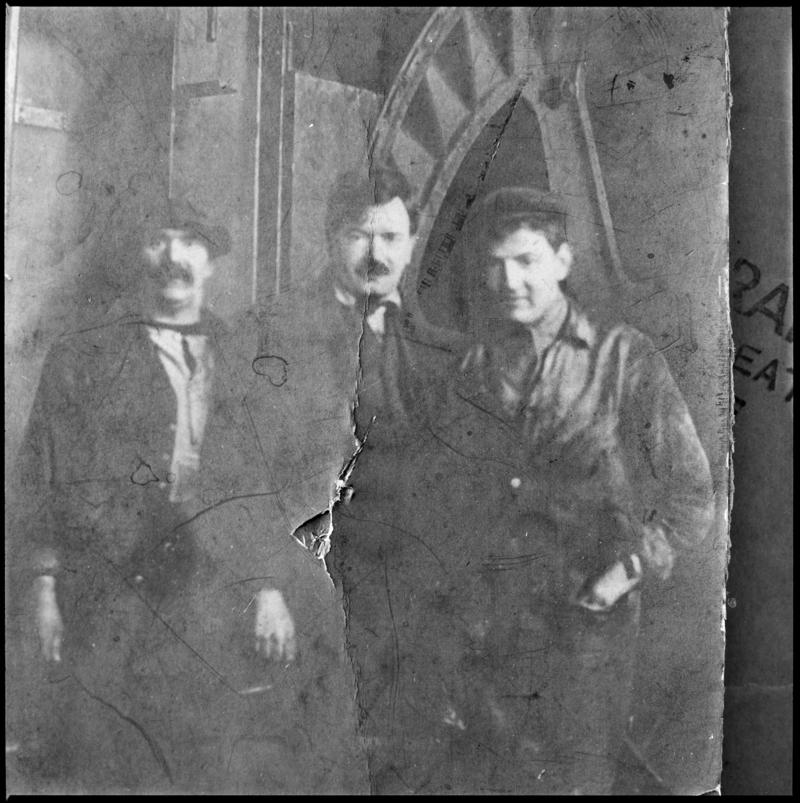 Black and white film negative showing a photograph of three men stood in front of a ?waddle fan, Deep Navigation Colliery.  &#039;Deep Navigation&#039; is transcribed from original negative bag.  Appears to be identical to 2009.3/1237.