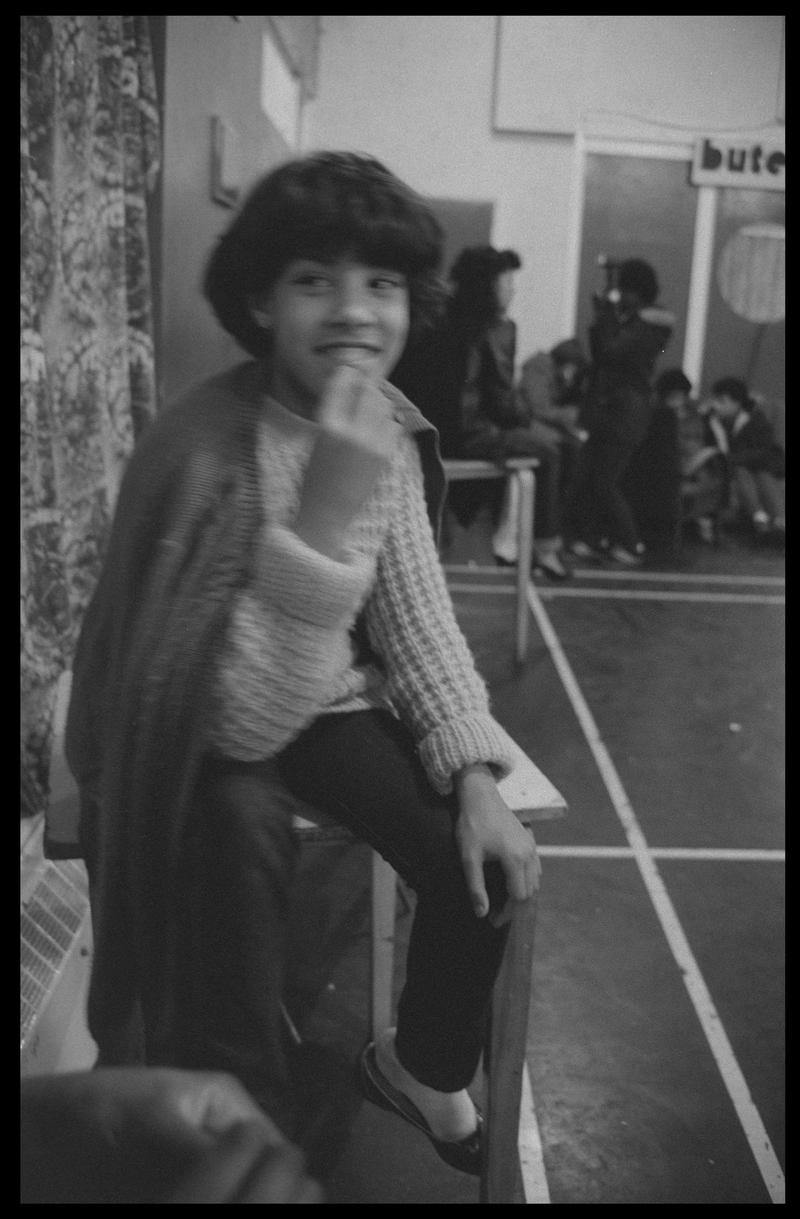 Girl sat at side of hall in Butetown Youth Club.