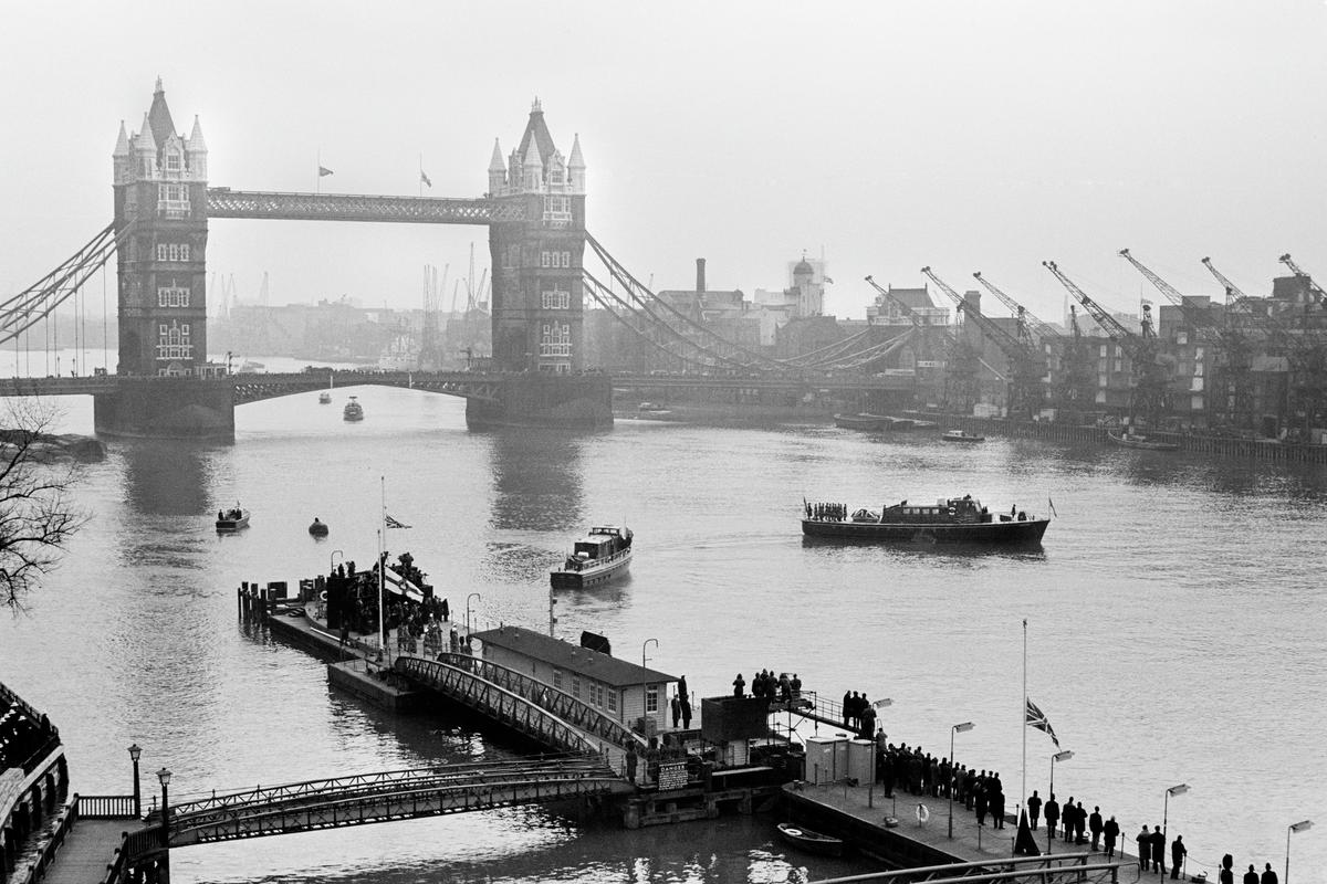 GB. ENGLAND. London. Winston CHURCHILL funeral. 3 January. As Churchill&#039;s lead-lined coffin passed up the River Thames from Tower Pier to Festival Pier on the MV Havengore dockers lowered their crane jibs in a salute. 1965.