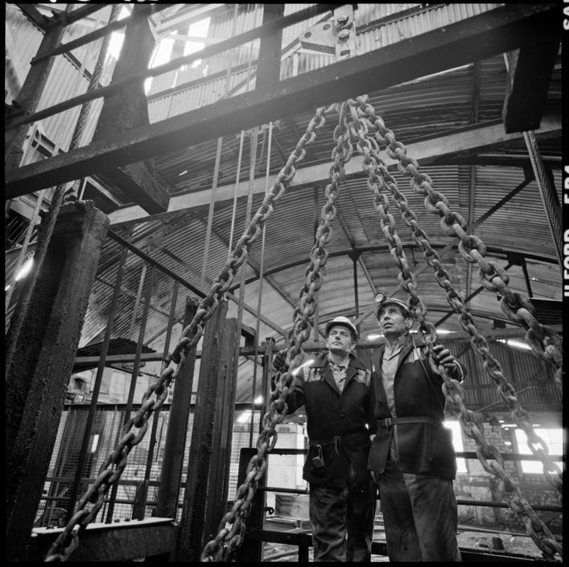 Black and white film negative showing men standing on top of cage at pit top, Big Pit Colliery January 1982.  &#039;Big Pit Blaenavon Jan 1982&#039; is transcribed from original negative bag.