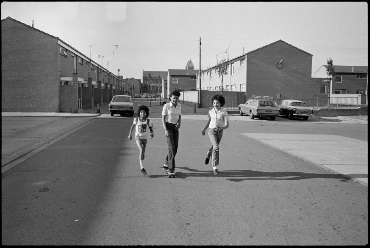 Three youngsters playing with a skateboard in Butetown.