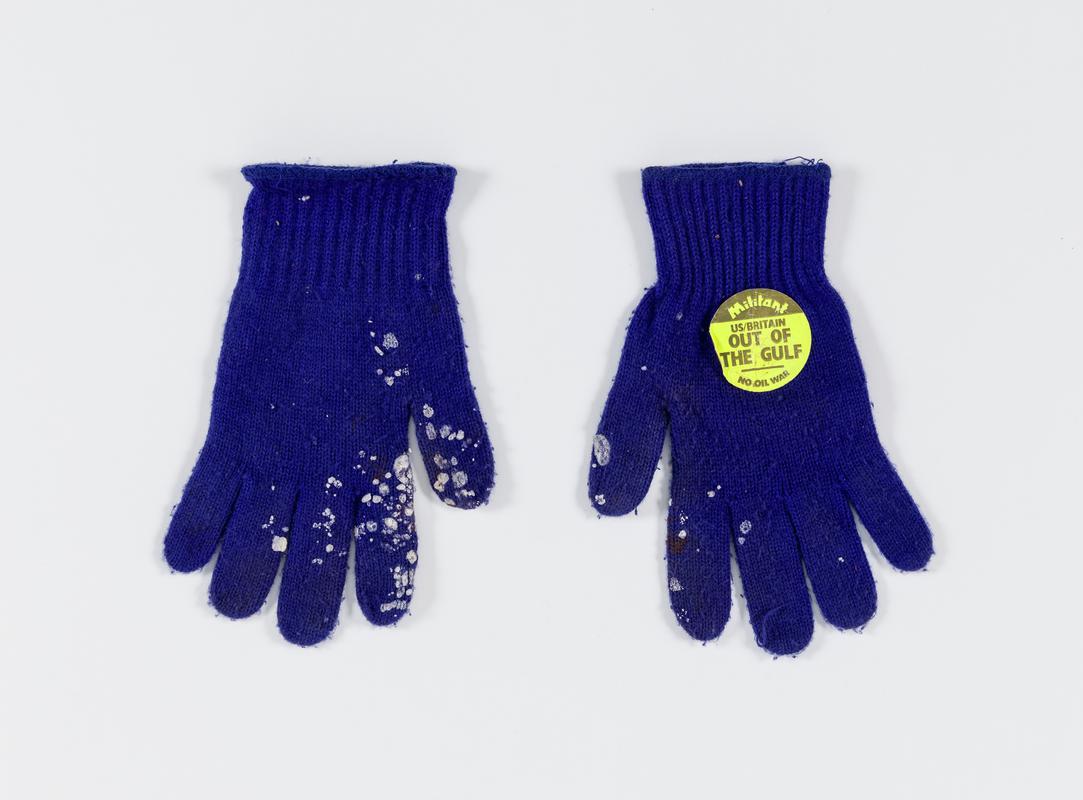 Pair of blue gloves. One has sticker saying &#039;Militant. US/Britain Out of the Gulf. No Oil War&#039;. Worn by Thalia Campbell, 2003.