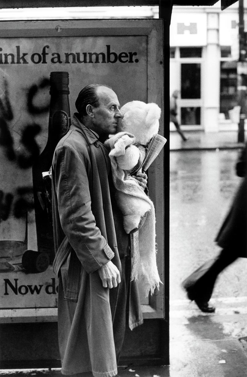 GB. WALES. Cardiff. A man, perhaps a father, clutches a large cuddly toy, as he waits for a bus to take him to some unknown destination. 1973.