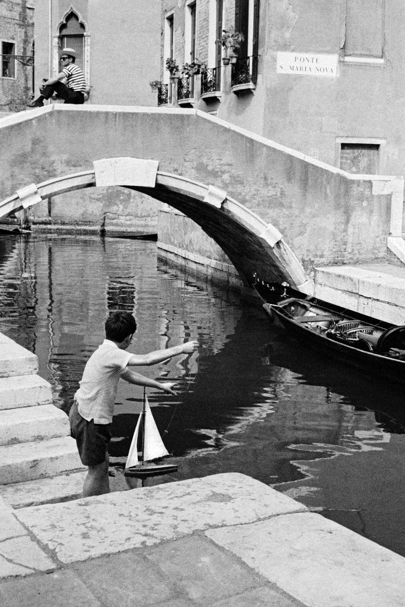 ITALY. Venice. Child playing with his model yacht in one of the canals of Venice. 1964.