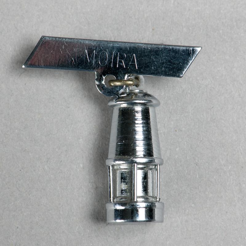Brooch consisting of a miniature miners lamp attached to a bar inscribed &#039;MOIRA&#039;.