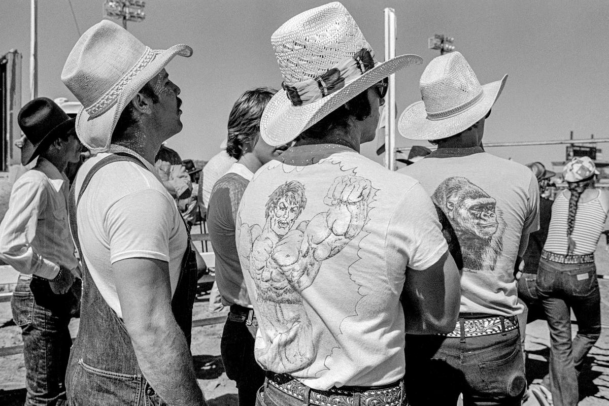 USA. ARIZONA. General.  Prescott&#039;s Frontier Days cowboy festival was the world&#039;s first rodeo and started in 1888.  Wild horse riding.  Spectators dress up as though competitors.  A picture of macho aggressiveness. 1980.