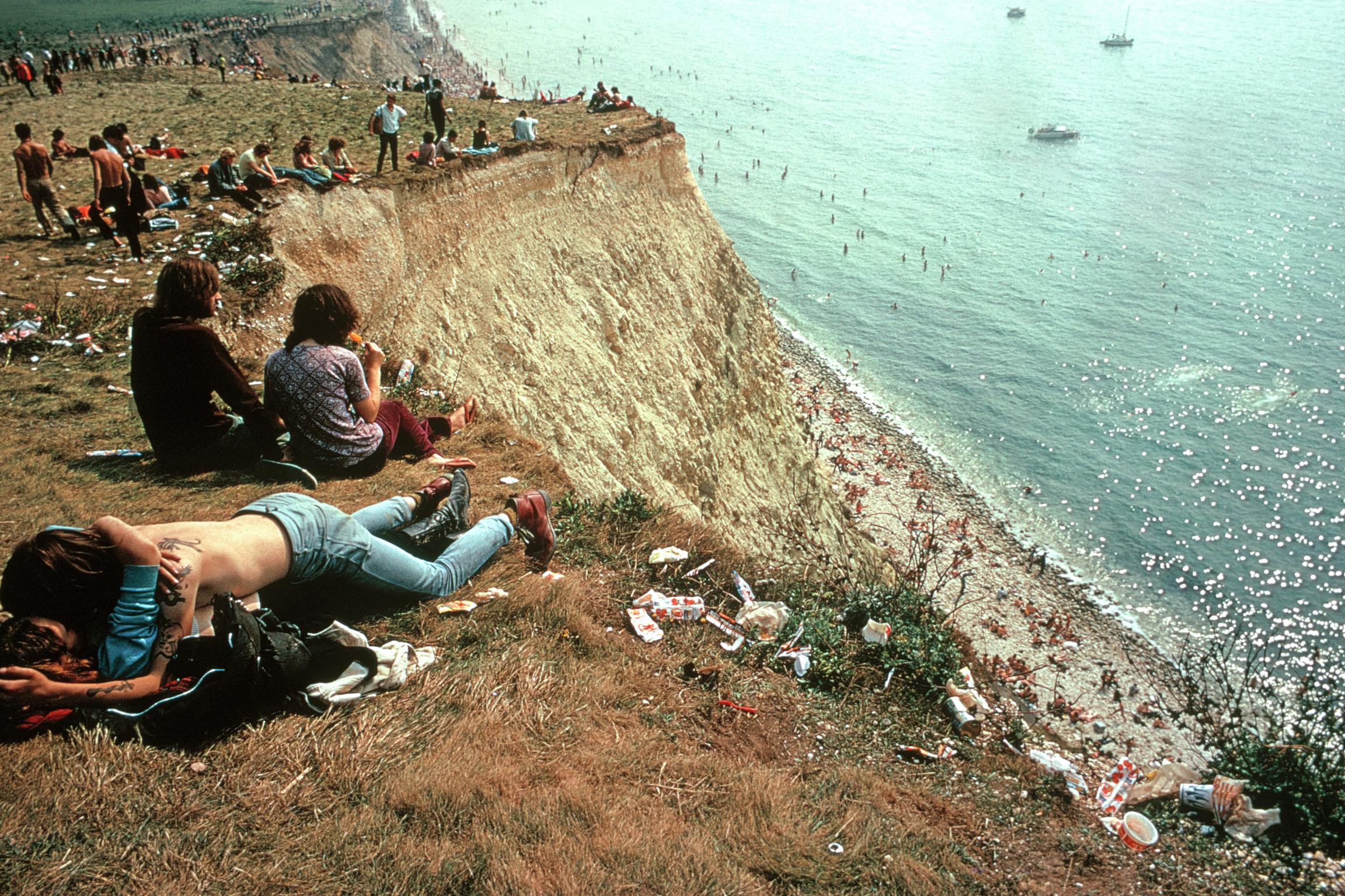 Isle of Wight Festival.  A young couple lying on the edge of a cliff amidst the litter