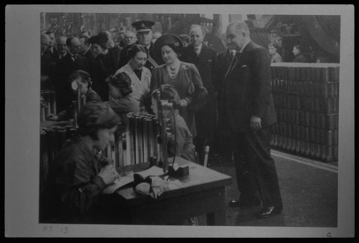 Film negative of a photograph showing visit of King George VI and Queen Elizabeth to Currans, Butetown during World War II. Queen Elizabeth is talking to staff.