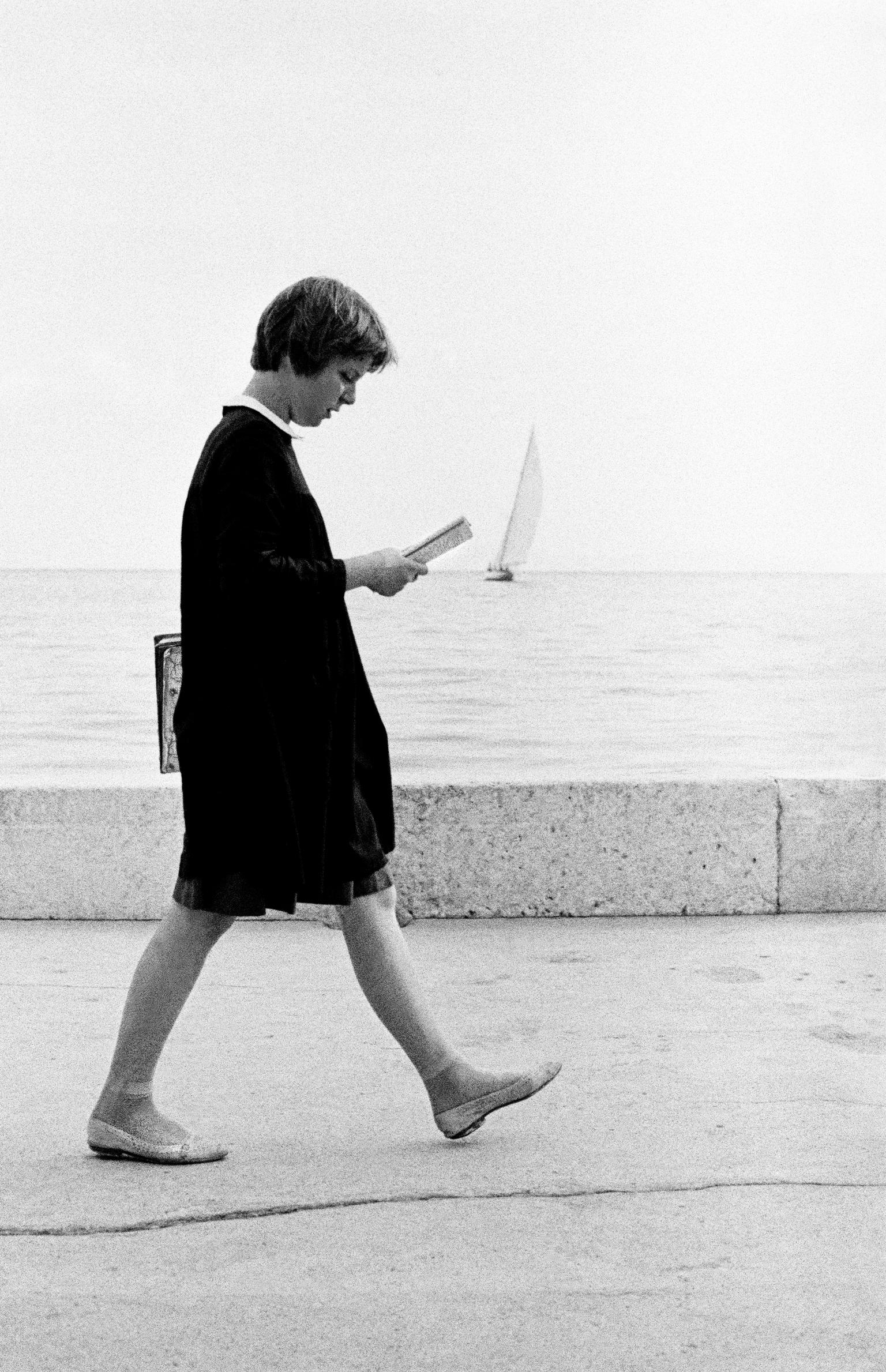 Student in the local school dress walks while reading of the sea front. Dubrovnik. Croatia