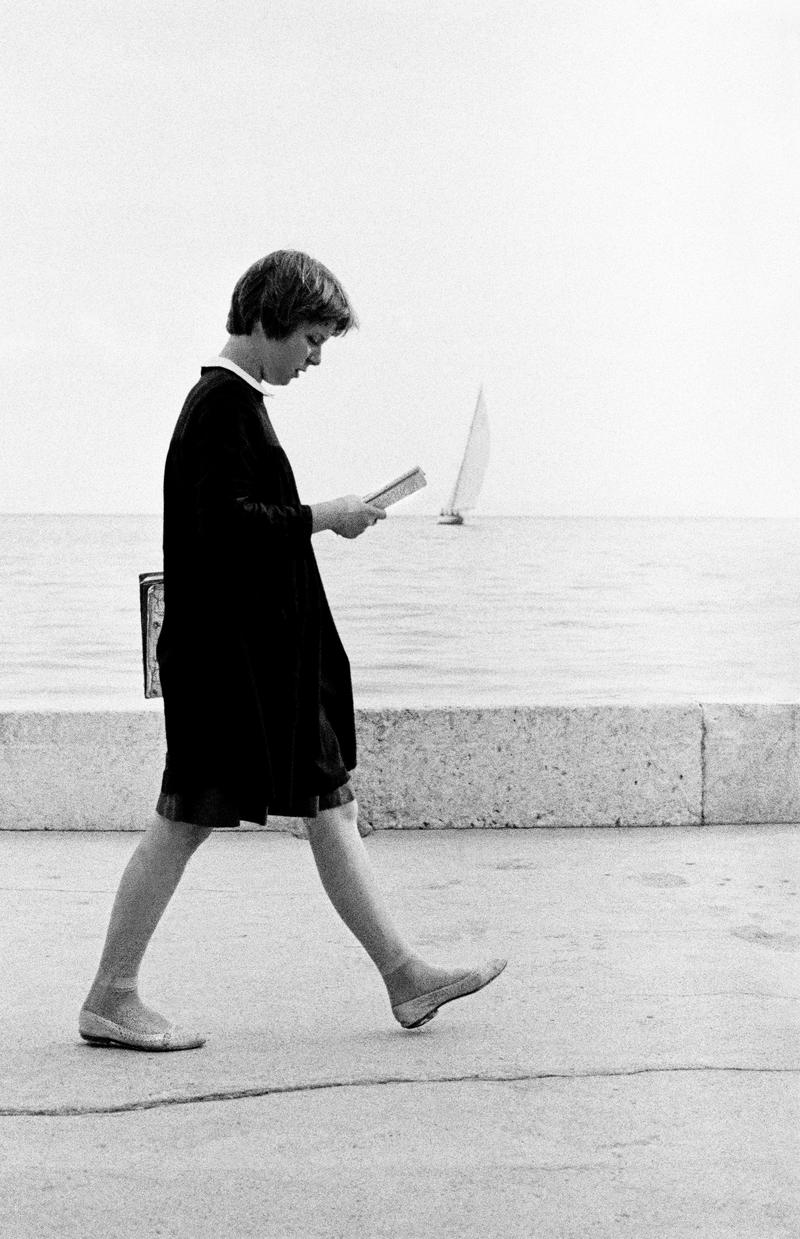 CROATIA (was Yugoslavia). Dubrovnik. Student in the local school dress walks while reading of the sea front. 1964.