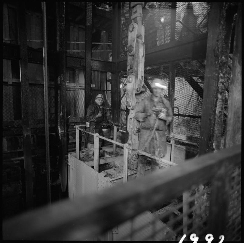 Black and white film negative showing men carrying out maintenance work near the skip at pit bottom, Lady Windsor Colliery.
