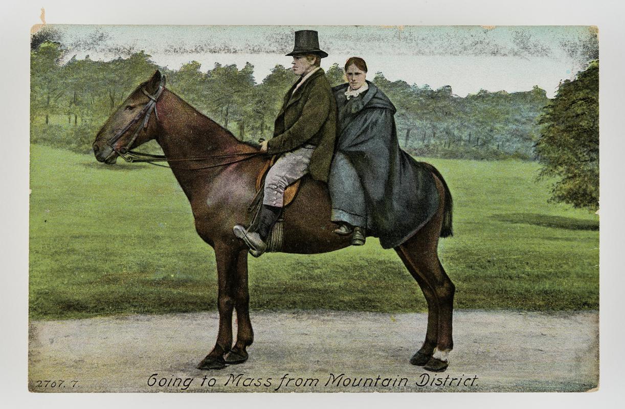 Tinted postcard of man &amp; woman sitting on a horse, entitled &#039;Going to Mass from mountain district&#039;.