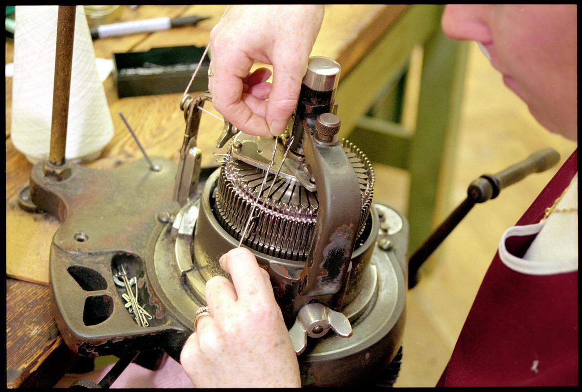 Close-up of Andrea Rockman turning needles on a sock knitting machine to form rib stitch. Corgi Hosiery Ltd factory, Ammanford, 1 July 2002.