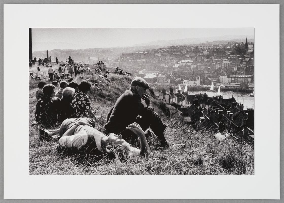 A sunny sunday afternoon brings tourists and residents on to the hill overlooking Whitby harbour to relax and dream. England, Whitby