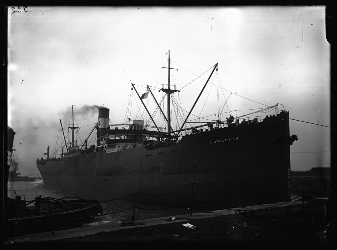 3/4 starboard bow view of S.S. DUNELMIA and tug sterns at Cardiff Docks, c.1936.