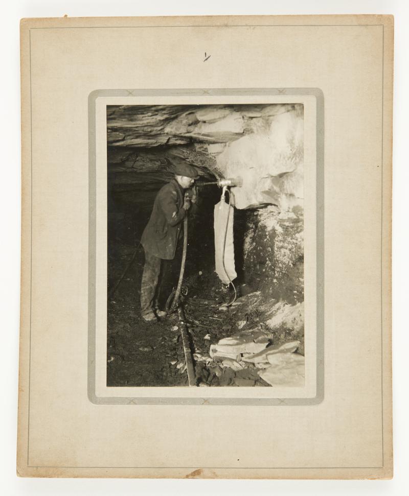 Photograph showing Stan Williams&#039; dust trap invention in action underground. Mounted on card.