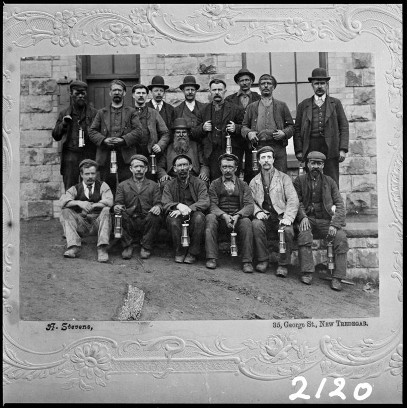 Black and white film negative of a photograph showing a group of New Tredegar miners.  Caption on photograph reads &#039;35 George St, New Tredegar&#039;.  &#039;Tredegar Miners&#039; is transcribed from original negative bag.
