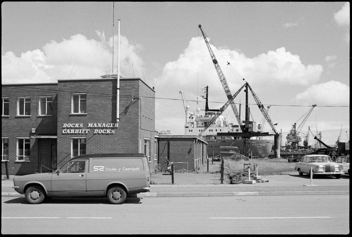 Exterior view of Cardiff Docks Manager&#039;s building with Cardiff Docks van parked outside and a Russian ship in dock in the background.