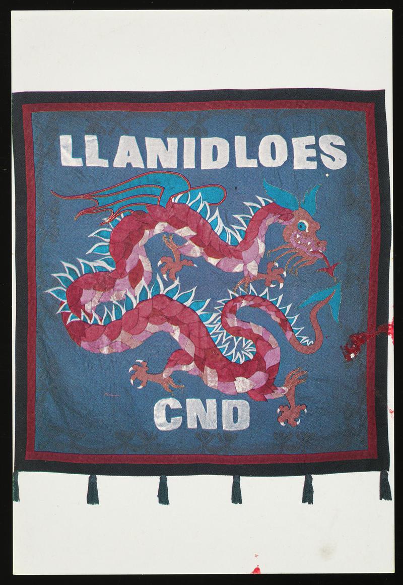 Colour postcard of a Llanidloes CND banner. Original banner Designed by Gini Wade &amp; Ron Simpson and made by The Llanidloes CND group. The dragon, the heraldic animal of Wales, is a well-known symbol of positive energy.