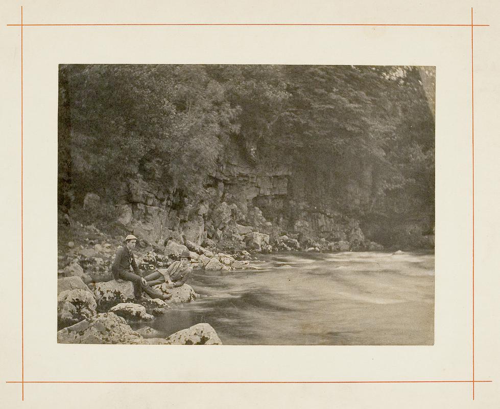 two boys on rocks beside river
