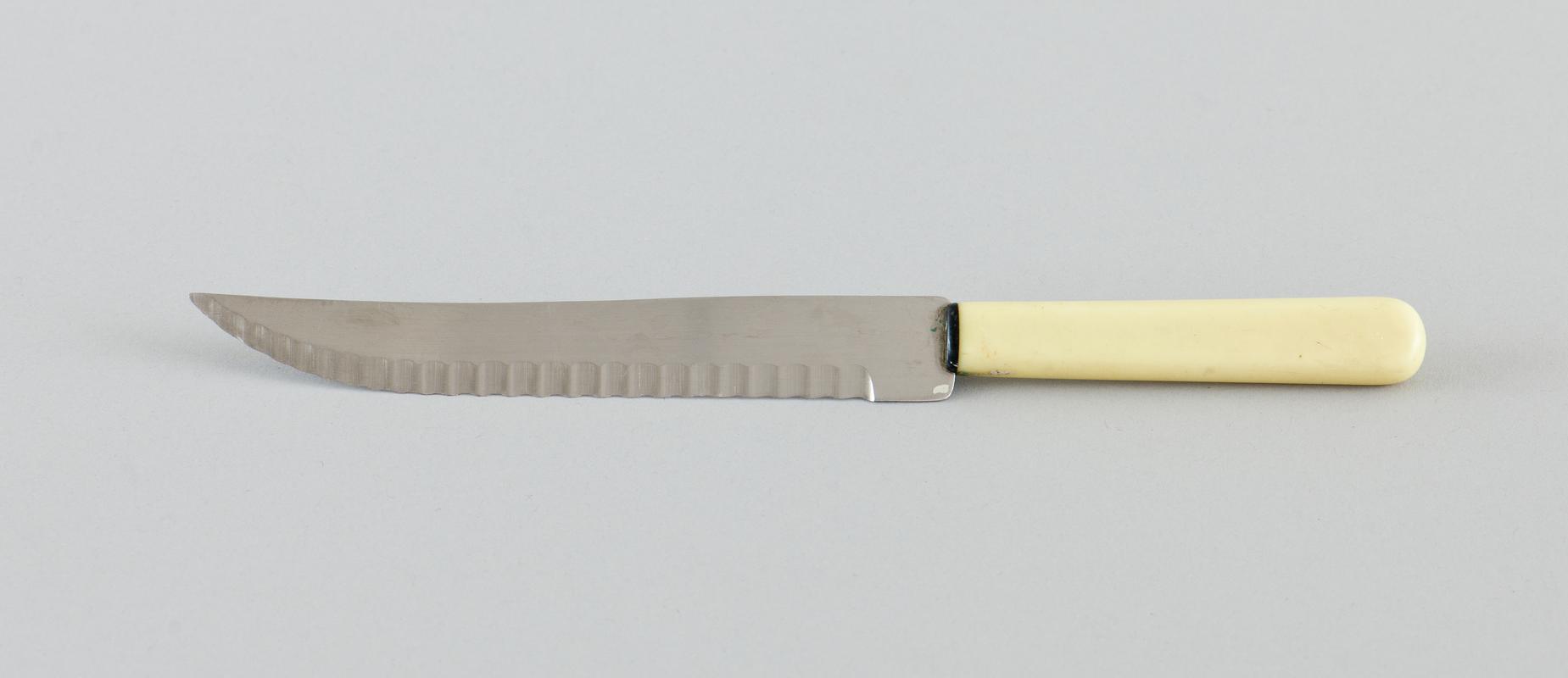 Preparation knife. Serrated blade on curved edge with cream plastic handle.