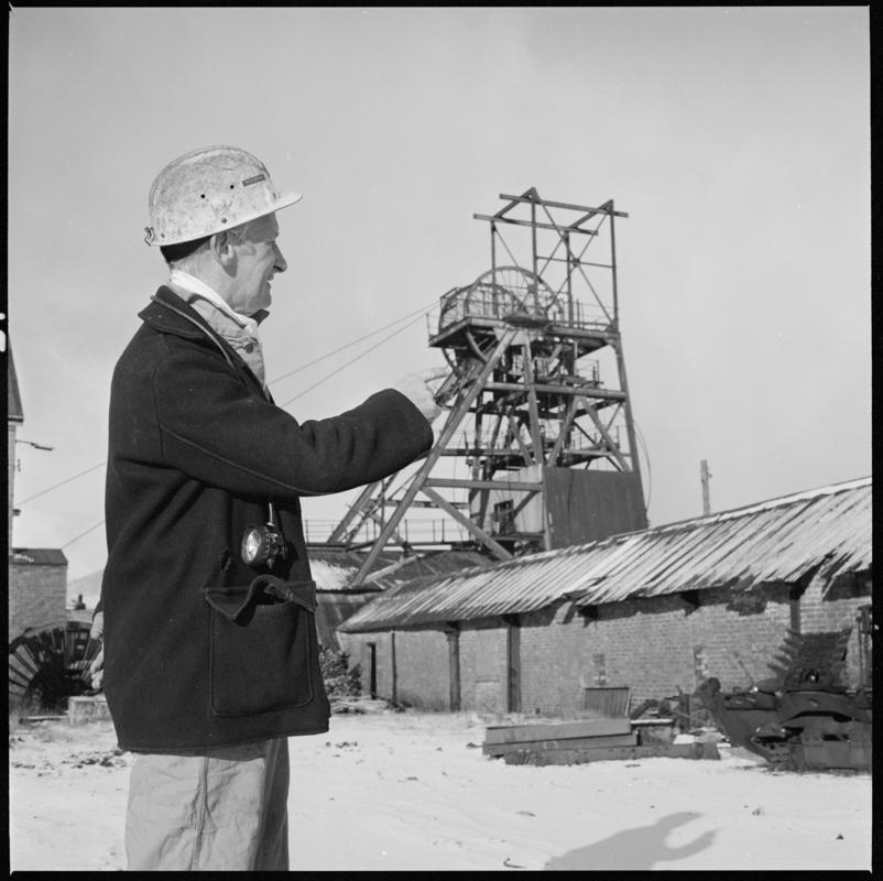 Black and white film negative showing Glyn Morgan, NCB Manager with the headgear in the background, Big Pit Colliery.