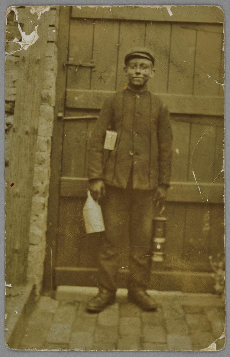 Rhys Wallace Jones of Aberdare, taken the day after his thirteenth birthday in September 1909. This was his first day underground and he is seen with a water jack, food tin and lamp.