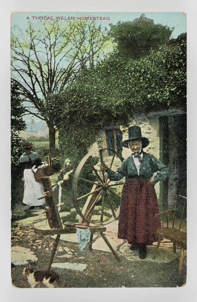 Ellen Lloyd, Bettws-y-coed in Welsh dress standing by spinning wheel outside cottage.  Title:  &#039;A Typical Welsh homestead&#039;.