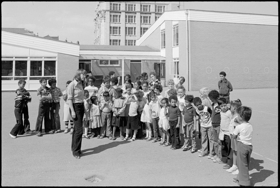 Group of children and teacher Mrs Davies in the playground at Mountstuart Primary School, Adelaide Street, Butetown.