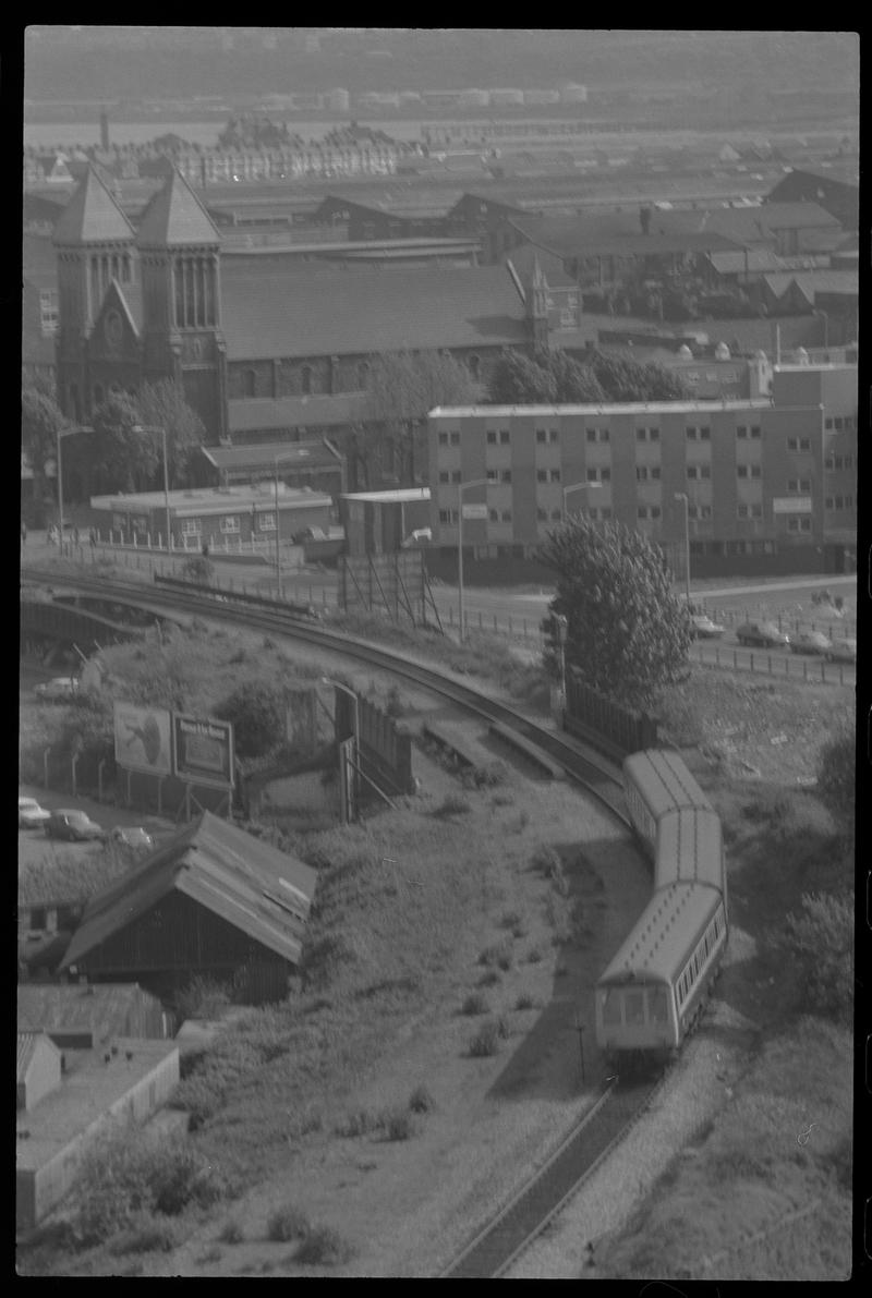 View of Bute Street, with passenger train on a single line to Bute Road in foreground and St Mary&#039;s Church in background.