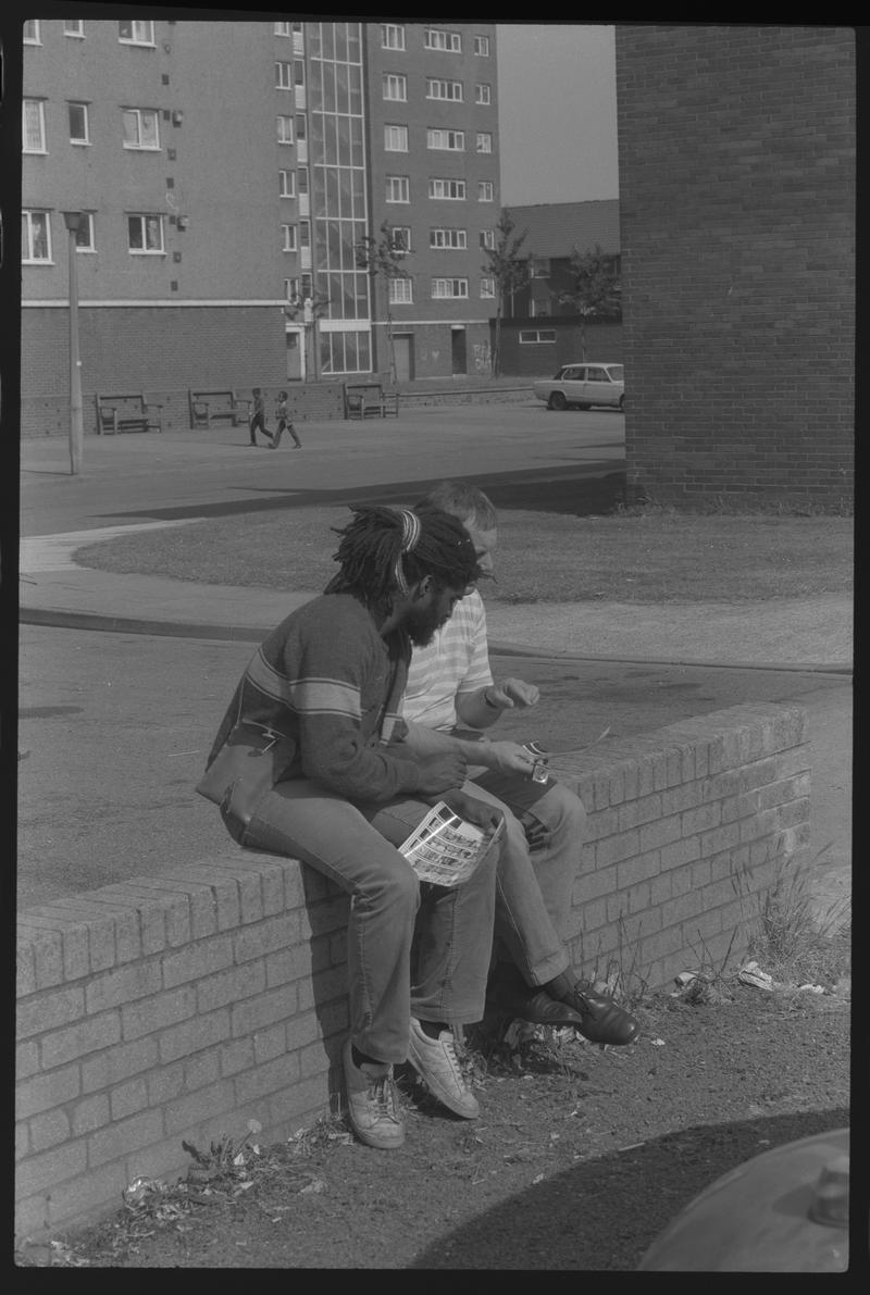 Two people sitting on wall near Loudoun Square Flats, Butetown.