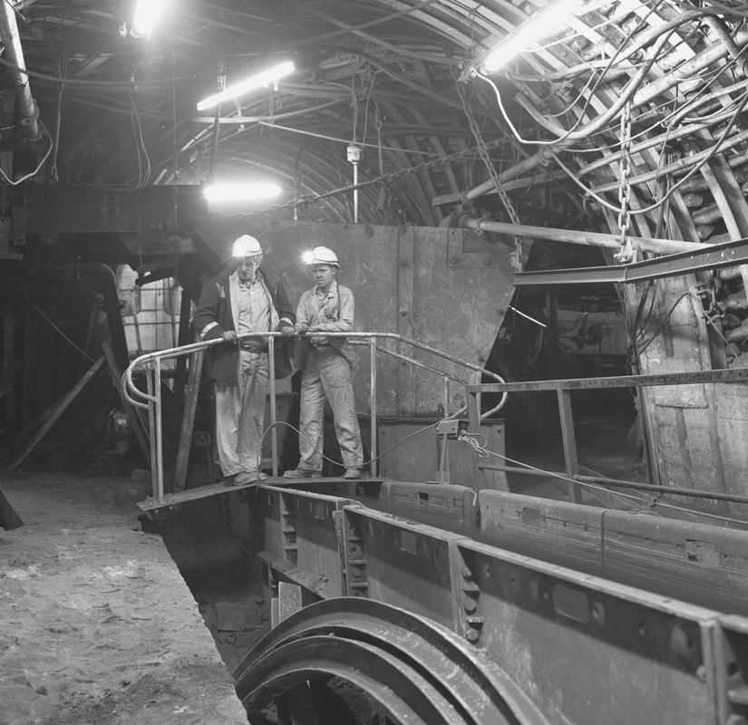 Black and white film negative showing two men stood on a bridge, underground at Oakdale Colliery, May 1980.  &#039;Oakdale May 1980&#039; is transcribed from original negative bag.