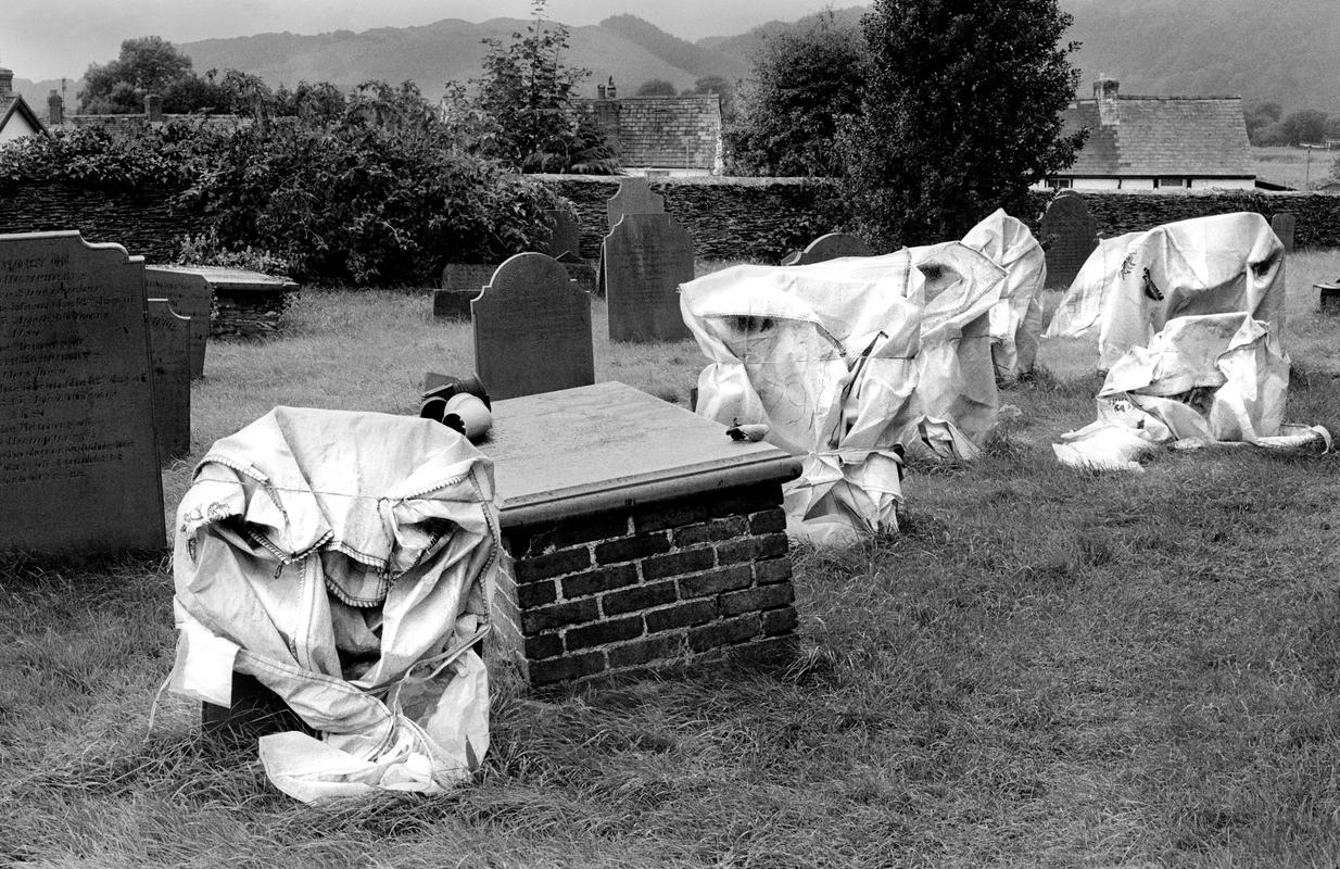 GB. WALES. Machynlleth. The graveyard. Grave stones being repaired, looking as though ghosts from the past are apearing from the ground. 1999.