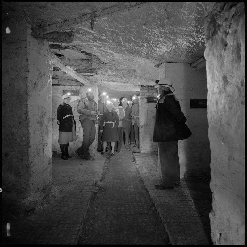 Black and white film negative showing visitors to Big Pit Mining Museum with guide at the underground stables, 1983.  &#039;Big Pit&#039; is transcribed from original negative bag.