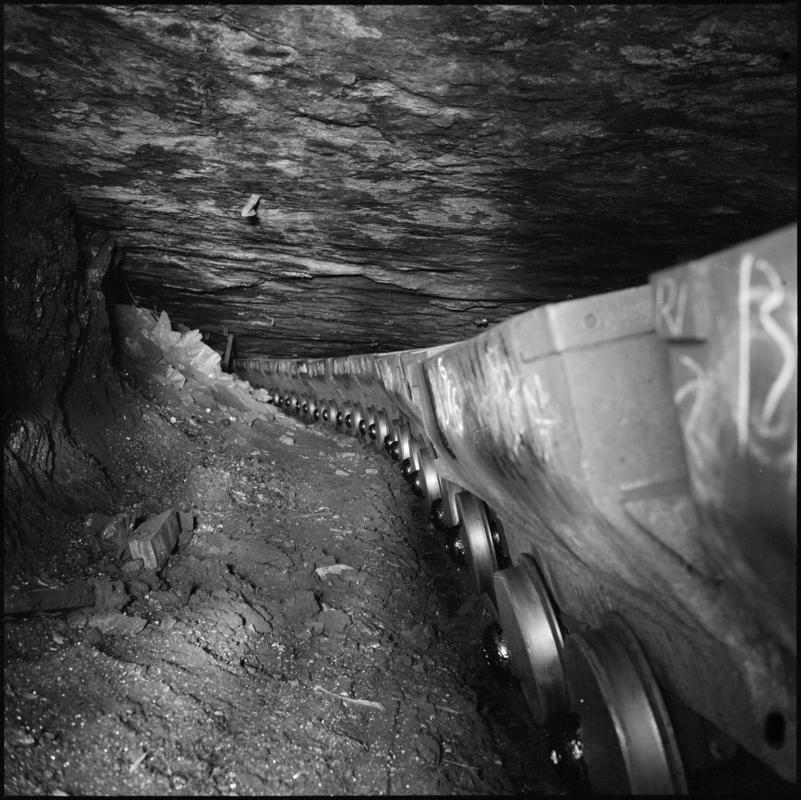 Black and white film negative showing a line of drams in the Graigola Seam, Graig Merthyr Colliery.  Note the unsupported sandstone roof.  &#039;Graig Merthyr&#039; is transcribed from original negative bag.