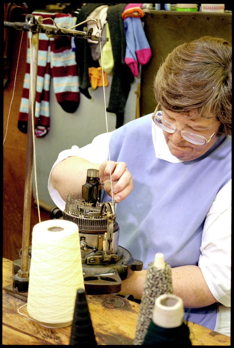 Margaret Evans lifting needles on a sock knitting machine to form cable stitch. Corgi Hosiery Ltd factory, Ammanford, 1 July 2002.