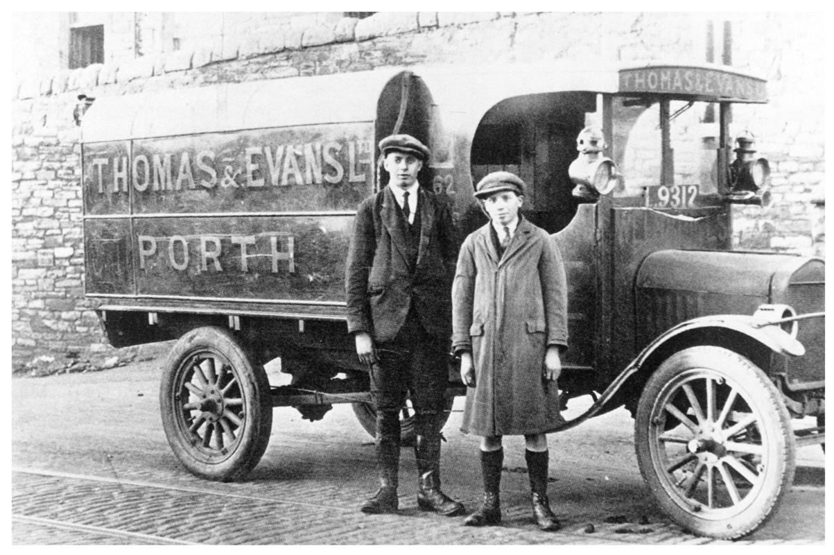 Two men standing in front of a Thomas &amp; Evans Ltd. delivery van.