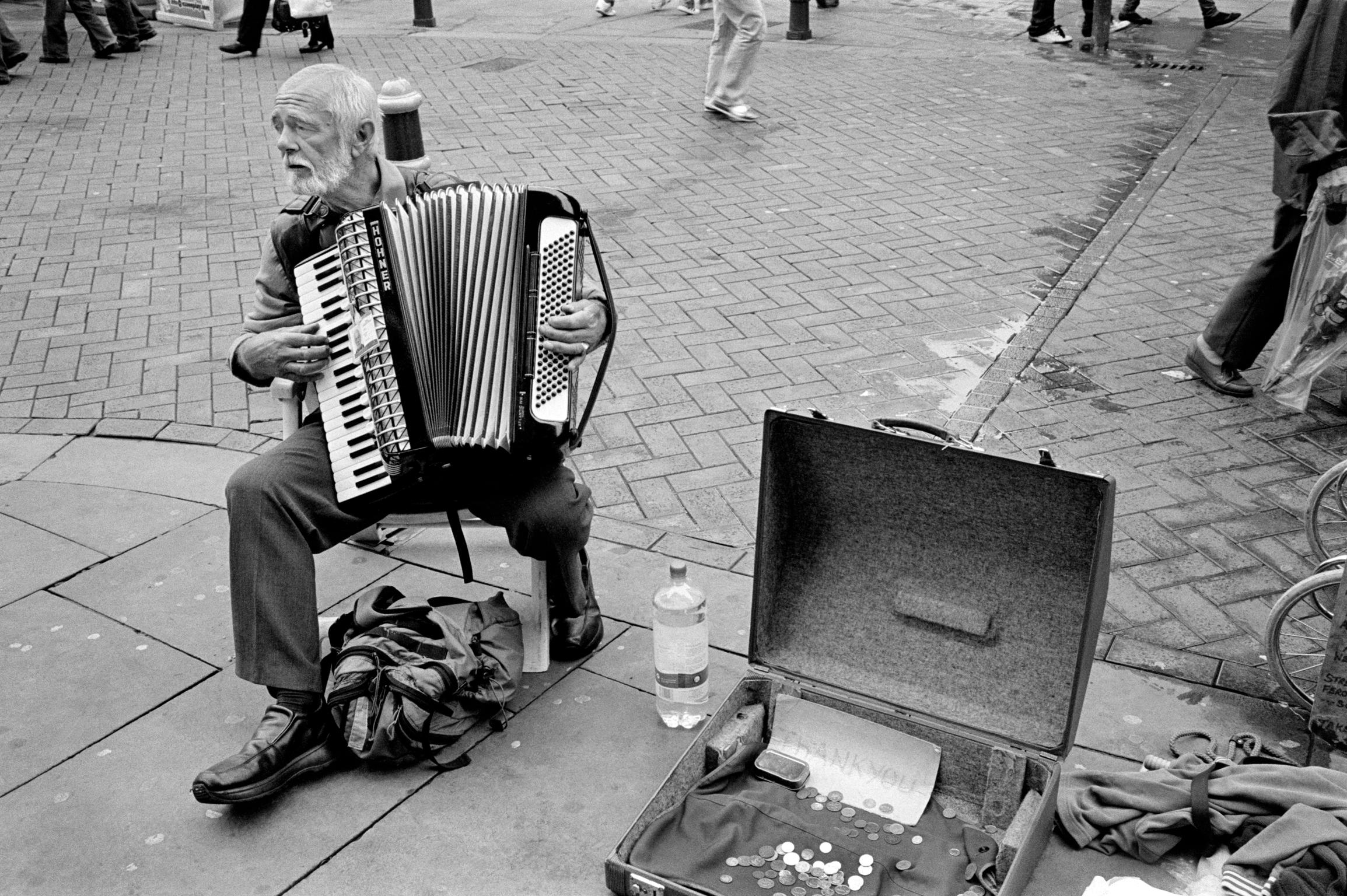 Busker playing music in the main street. Newport, Wales