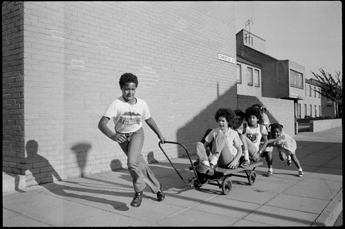 Children riding on an old trolley on Christina Street, Butetown.