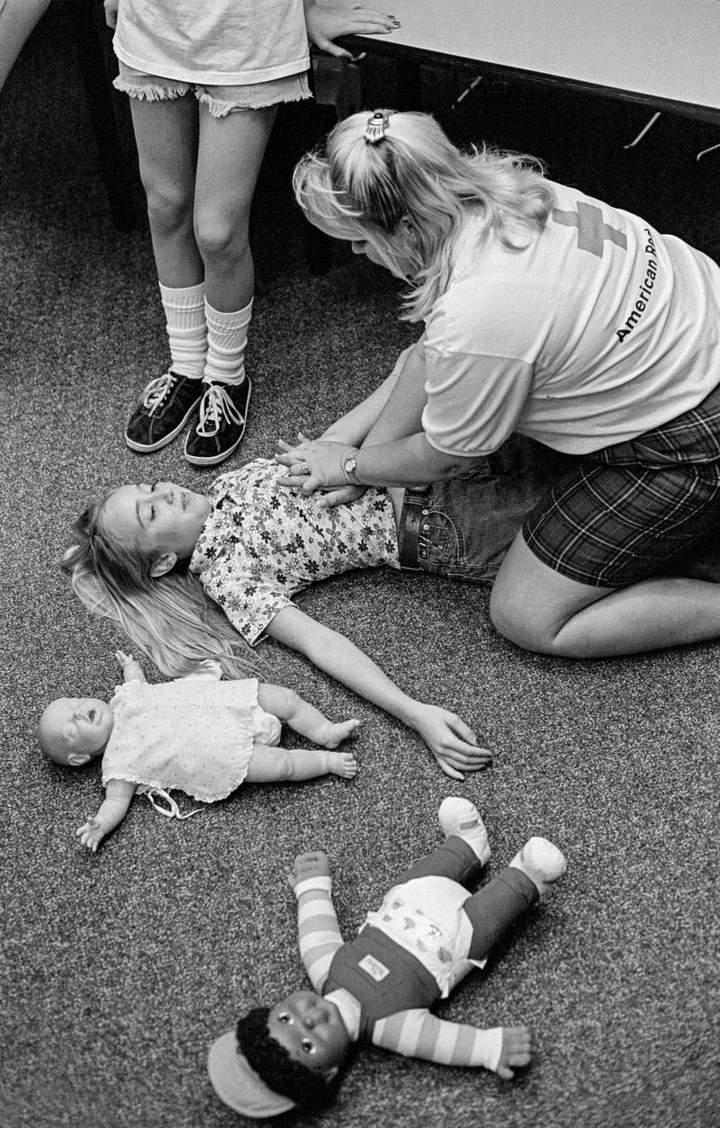 USA. ARIZONA. Phoenix. Red cross baby sitting classes. Red Cross workers run baby sitting classes in the Phoenix chapter. The students are aged from 11-15. They learn how to protect children from accidents and injury. They learn first aid for choking and bleeding, mouth to mouth and the Heimlich manoeuvre, and dealing with crying and changing diapers etc. At the end of the course they receive a certificate. Here learning how to hold a baby. Here we see Abdominal thrusts being taught. 1997.