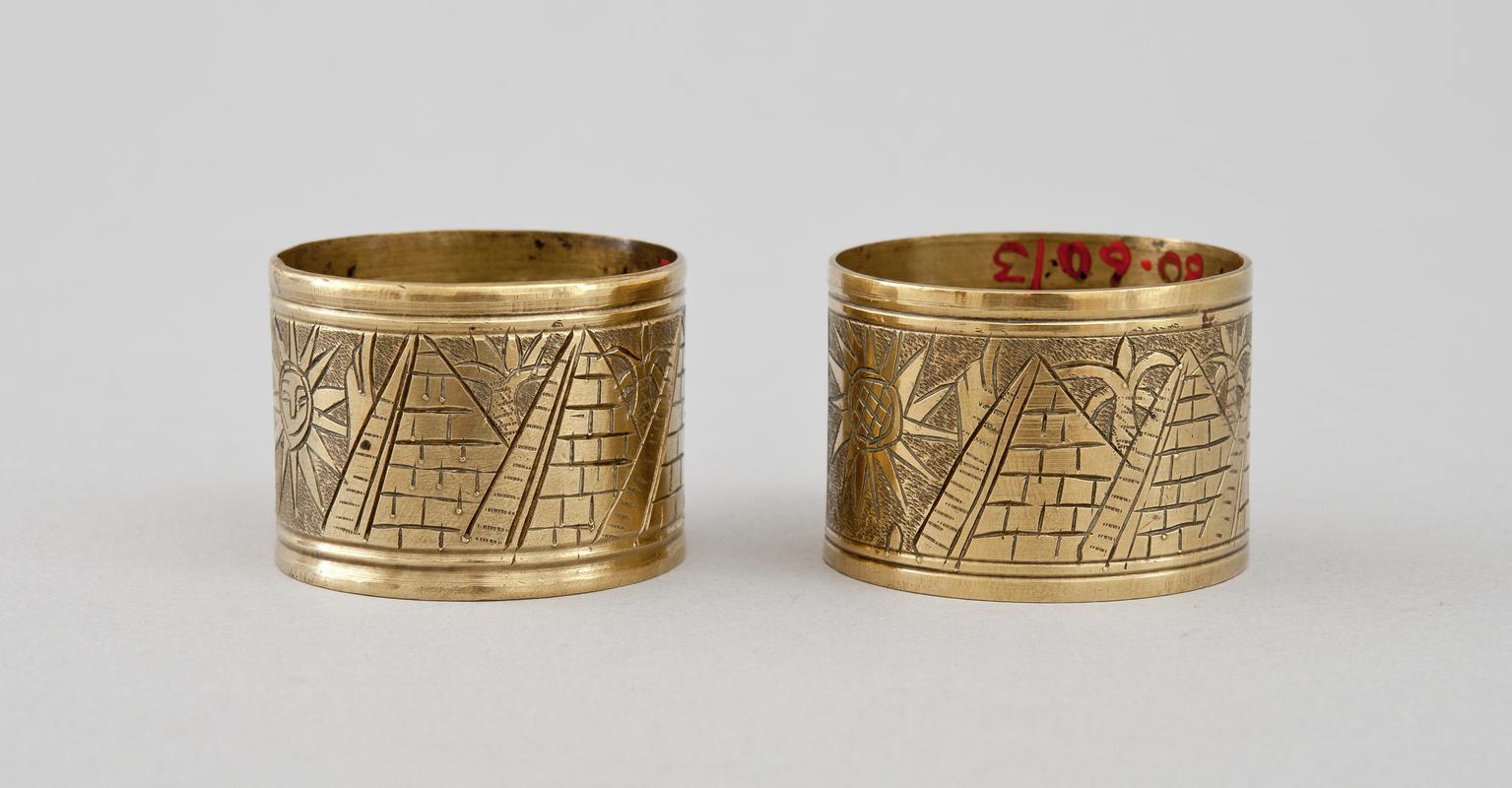 Brass napkin ring made from a shell case. Engraved with Egyptian motifs of pyramids and sphinx.