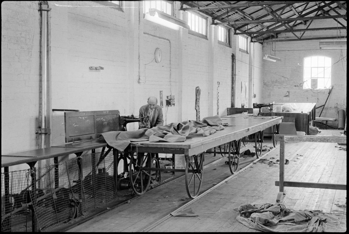 Mr Hopwood machine stitching canvas on one of the sailmaking tables that run on a track at Jenkin Jones and Son sailmakers, 12 Hurman Street, Cardiff Docks.
