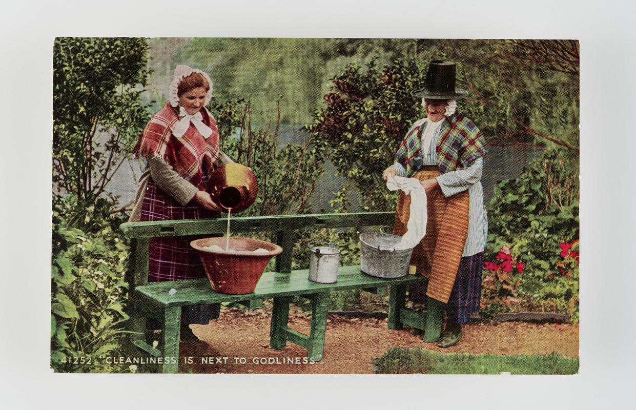 &quot;Cleanliness is next to Godliness&quot;.  2 women in Welsh costume washing in tubs on bench outdoors.