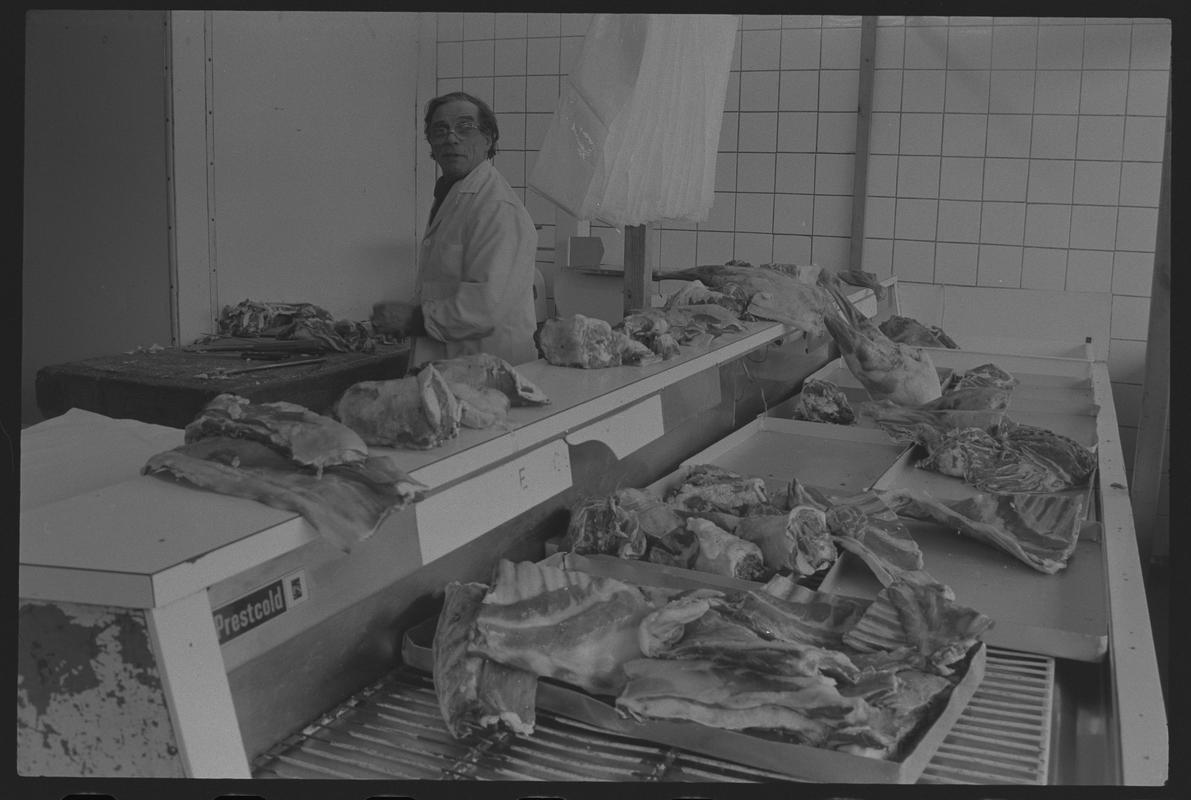 Butcher with meat ready for preparation in shop, Loudoun Square, Butetown.