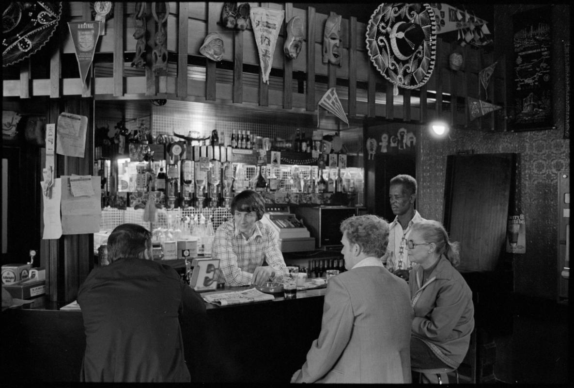 Interior view of the Ship &amp; Pilot public house showing people drinking at the bar, Mount Stuart Square, Butetown.