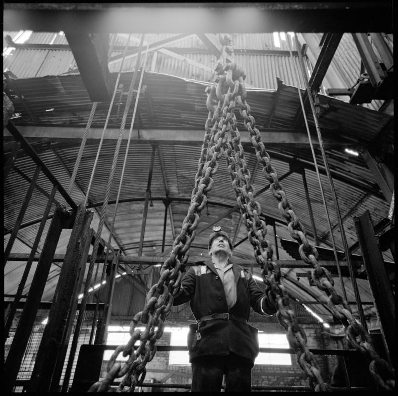 Black and white film negative showing man standing on top of cage at pit top, Big Pit Colliery January 1982.  &#039;Big Pit Blaenavon Jan 1982&#039; is transcribed from original negative bag.