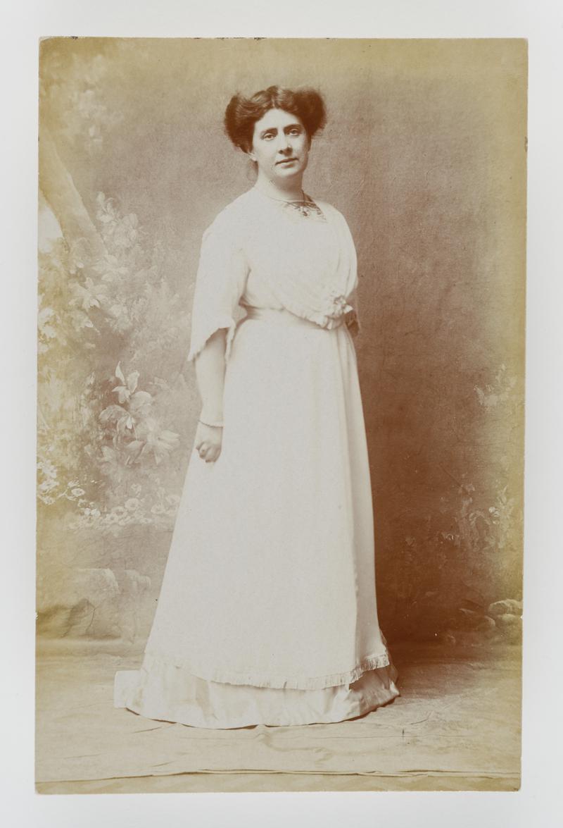 Studio photograph of a woman in long white dress.