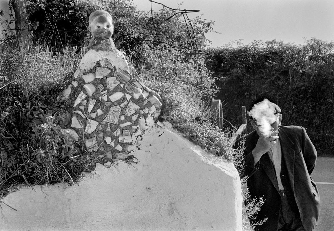 Old farmer with primitive sculpture he made for his garden near Aber Eiddy. Wales