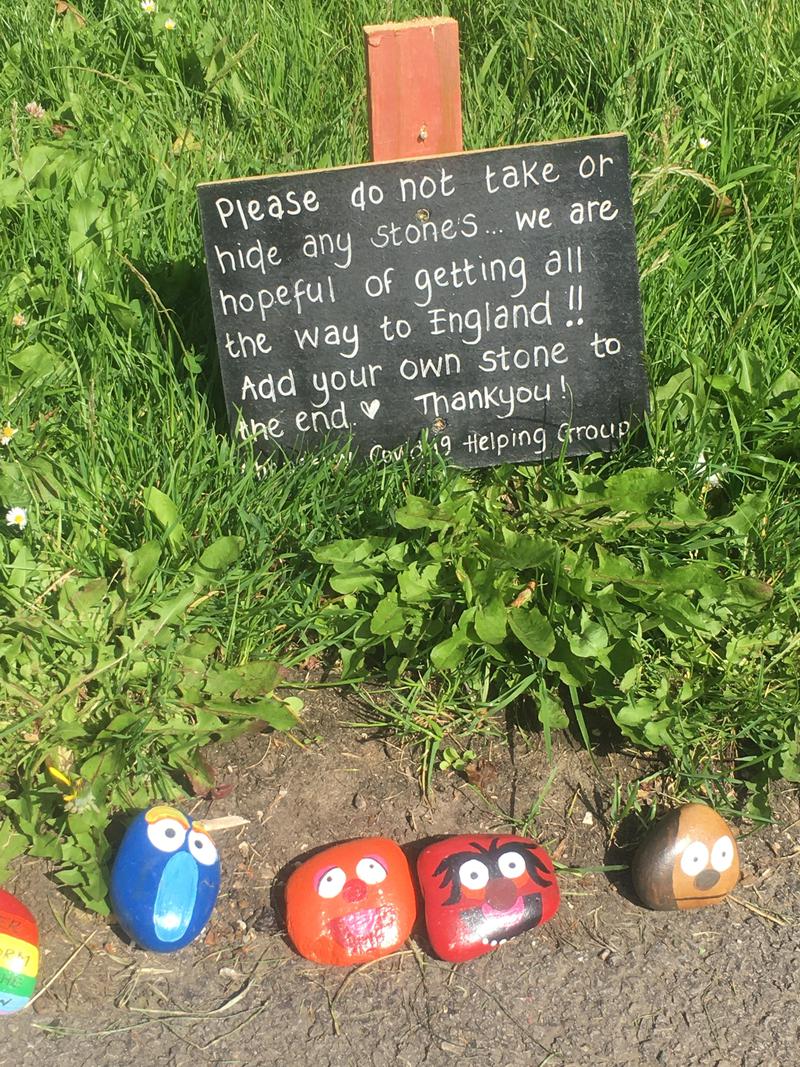 Sign beside painted pebbles reading &#039;please do not take or hide any stones &amp; we are hopeful of getting all the way to England!! Add your own stone to the end. Thank you! Chepstow Covid 19 Helping Group&#039;.